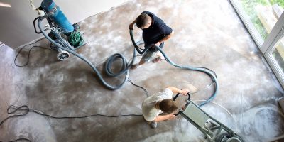 Construction worker in a family home living room that grind the concrete surface before applying epoxy flooring.Polyurethane and epoxy flooring.Concrete grinding.